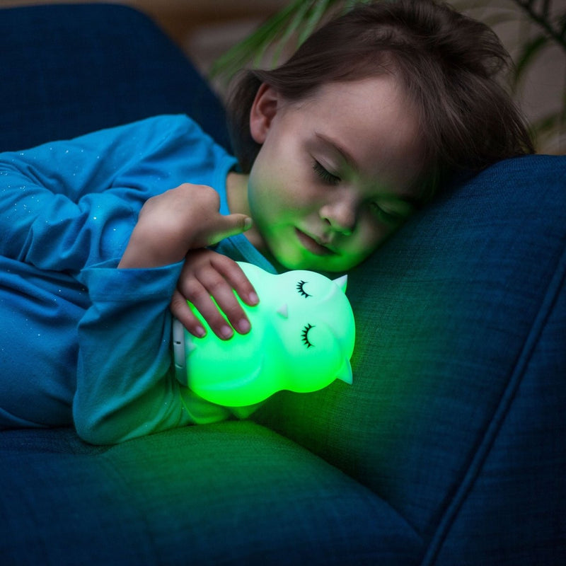 Child sleeping and holding an owl nightlight speaker shining green light